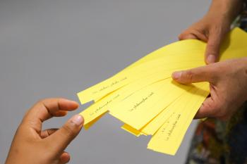 main tirant un petit papier jaune sur lequel est inscrit un thème à discuter lors de l'atelier philo